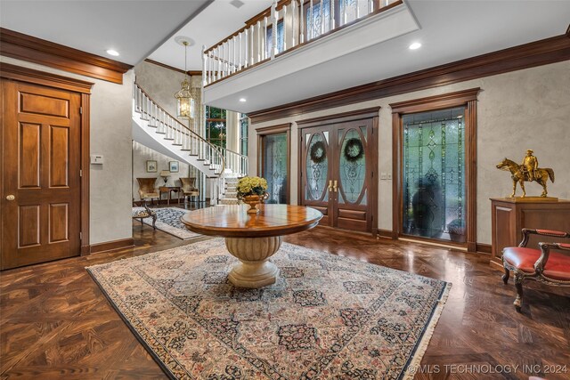 entrance foyer featuring dark parquet floors, crown molding, and a notable chandelier