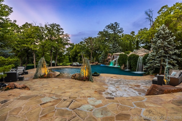 pool at dusk featuring a patio and pool water feature