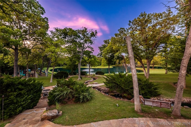 view of community featuring a lawn, a water view, and a playground