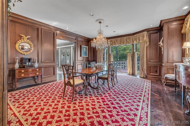 dining room featuring a chandelier, ornamental molding, and a decorative wall