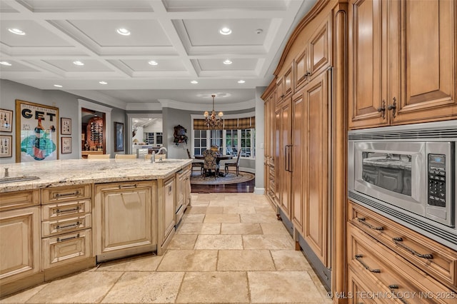 kitchen featuring recessed lighting, stone tile flooring, stainless steel microwave, a sink, and light stone countertops