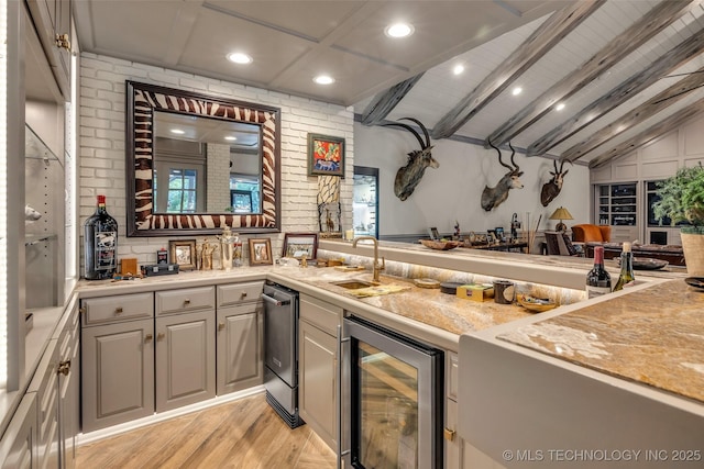 kitchen with beverage cooler, light countertops, a sink, and light wood-style floors