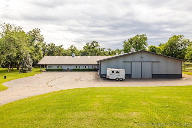 view of front of house with a garage, an outbuilding, an outdoor structure, and a front lawn