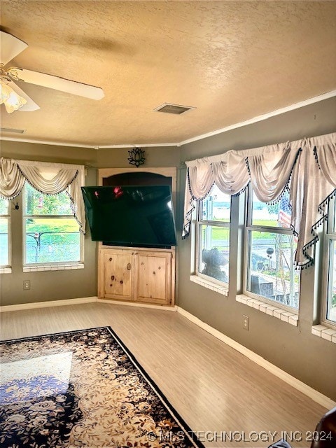 interior space featuring ceiling fan, wood-type flooring, and a textured ceiling