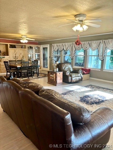 living room with ceiling fan, a textured ceiling, and plenty of natural light