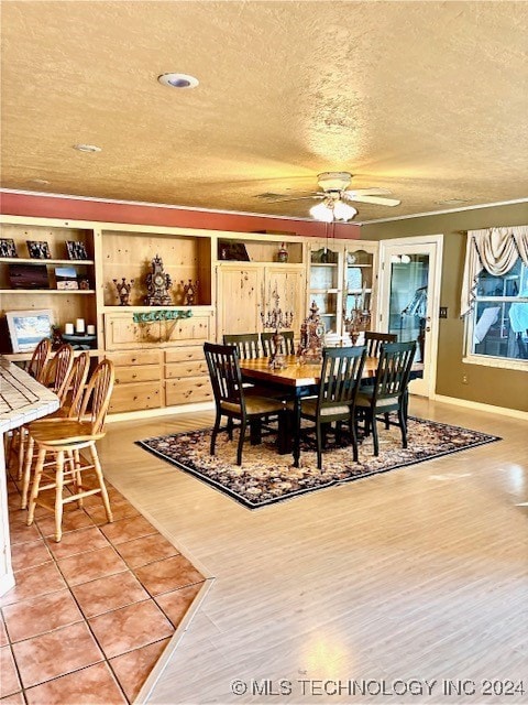 dining room with a textured ceiling, light wood-type flooring, and ceiling fan