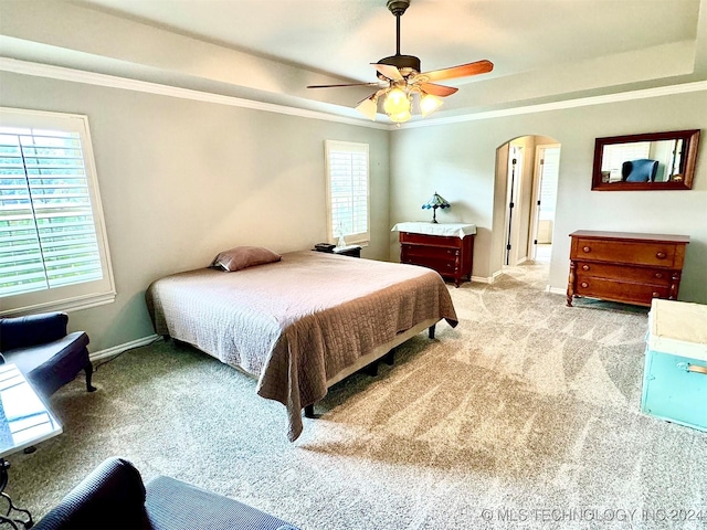 bedroom with light carpet, arched walkways, a raised ceiling, and ornamental molding