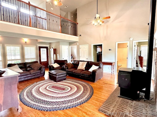 living area with ceiling fan, wood finished floors, and a wood stove