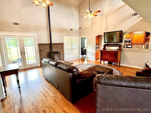 living area featuring a towering ceiling, light wood finished floors, ceiling fan, and french doors