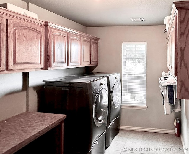 clothes washing area with cabinet space, visible vents, a wealth of natural light, and washer and dryer