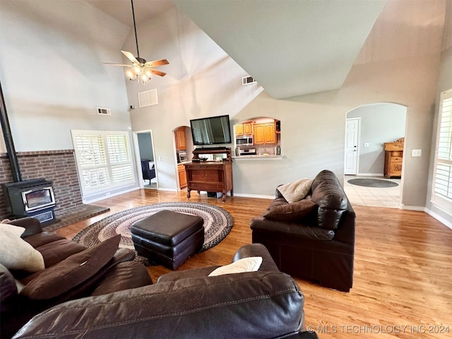 living room featuring light wood-type flooring, a wood stove, visible vents, and arched walkways