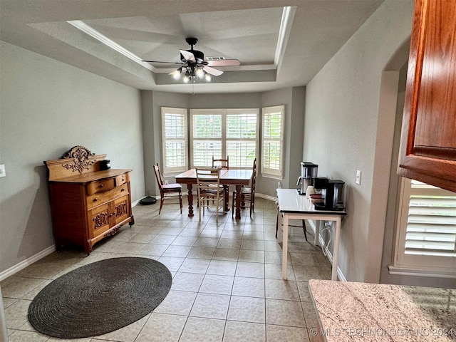 office space with a tray ceiling, crown molding, light tile patterned floors, a ceiling fan, and baseboards