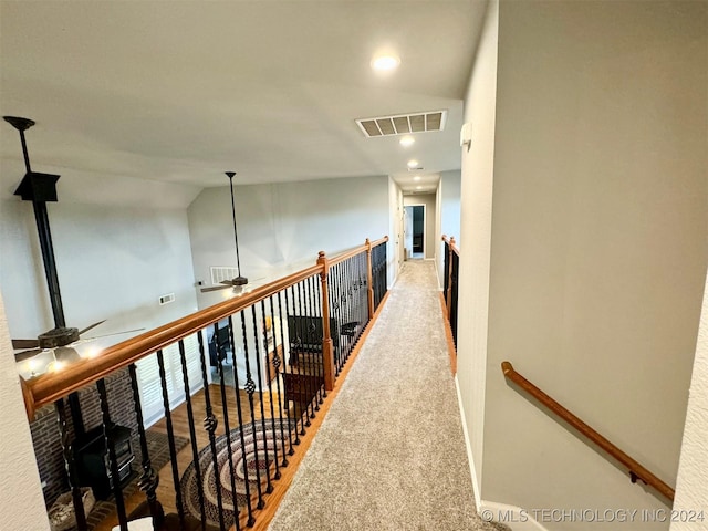 corridor with carpet floors, recessed lighting, visible vents, vaulted ceiling, and an upstairs landing