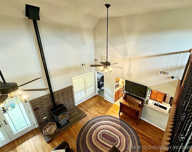 living room featuring visible vents, wood finished floors, a wood stove, and a ceiling fan