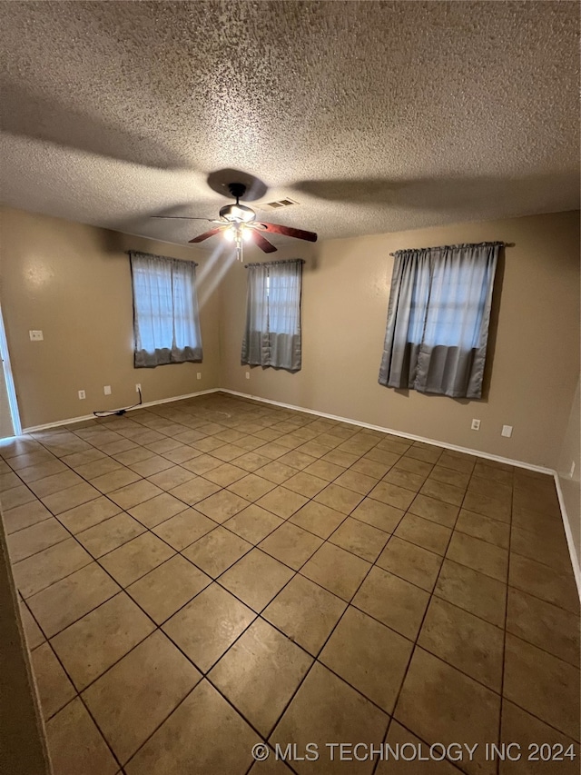 unfurnished room featuring ceiling fan, a textured ceiling, and tile patterned flooring