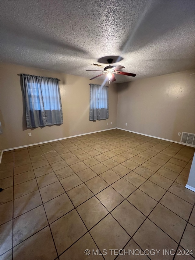 unfurnished room with a textured ceiling, tile patterned flooring, and ceiling fan