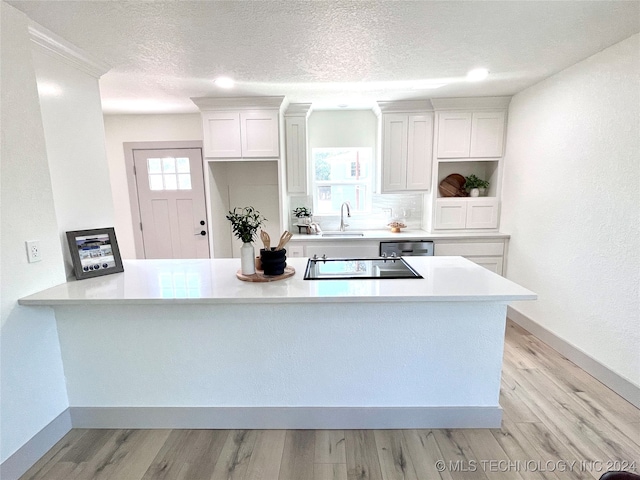 kitchen with light wood-type flooring, plenty of natural light, sink, and white cabinetry