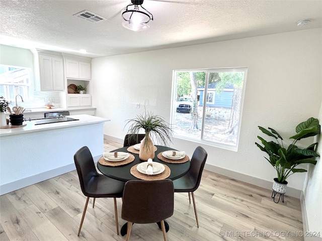 dining room with light hardwood / wood-style flooring, a textured ceiling, and sink