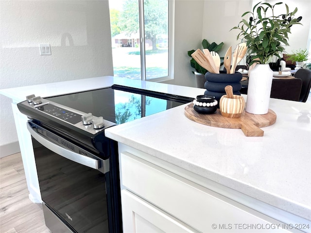 kitchen with white cabinets, range with electric stovetop, and light hardwood / wood-style floors