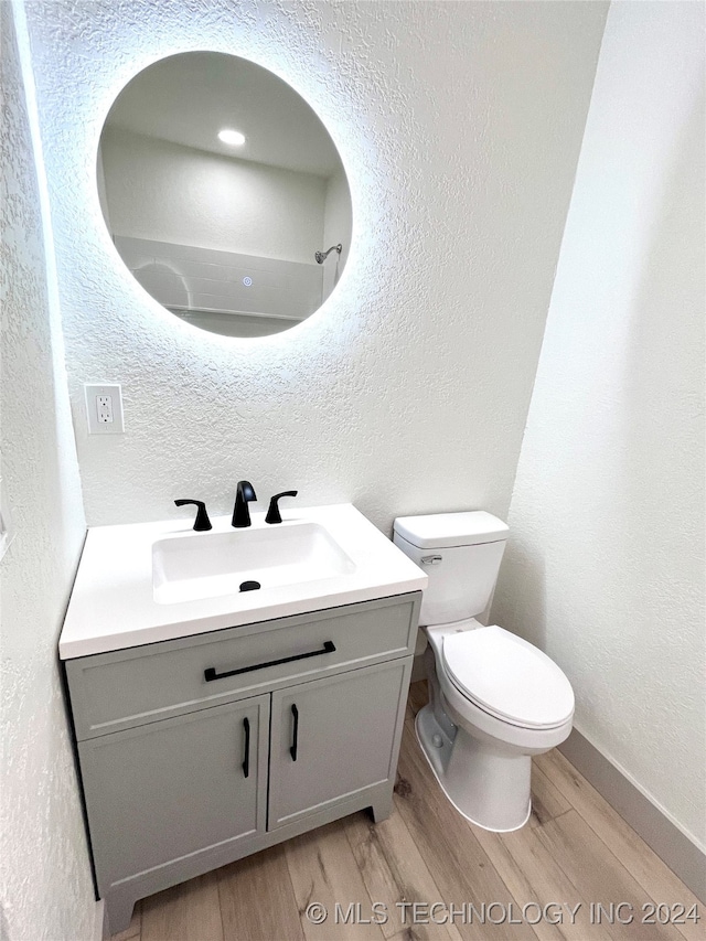 bathroom with toilet, vanity, and wood-type flooring