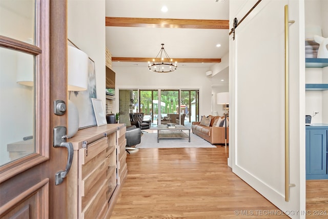 foyer featuring beamed ceiling, a barn door, a chandelier, and light hardwood / wood-style floors