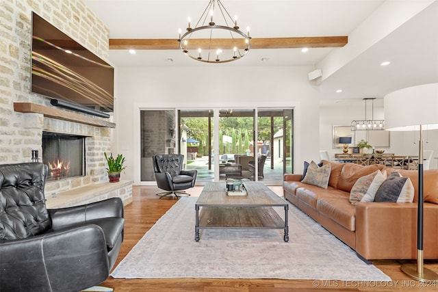 living room featuring hardwood / wood-style floors, beam ceiling, an inviting chandelier, a fireplace, and brick wall