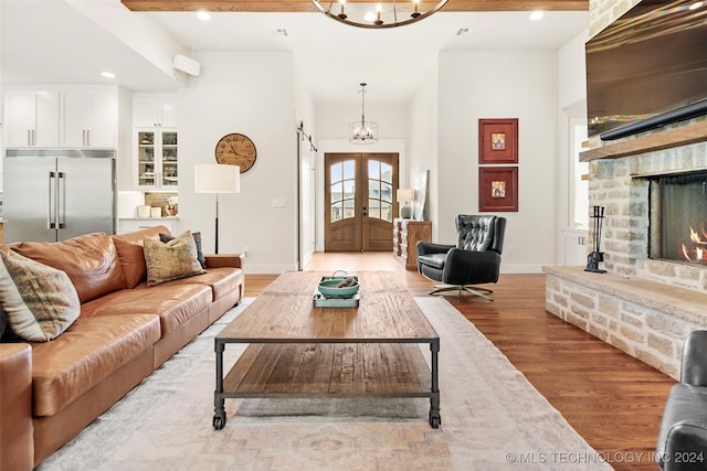 living room featuring light hardwood / wood-style flooring, a chandelier, and beam ceiling