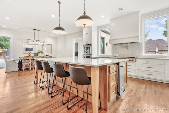 kitchen with white cabinetry, light wood-type flooring, and a healthy amount of sunlight