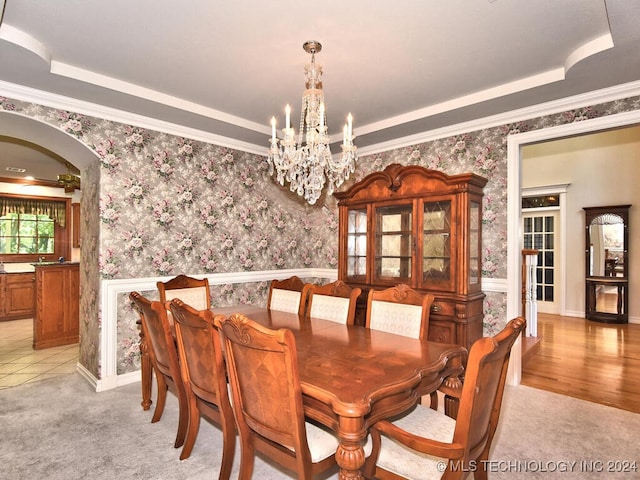 tiled dining room with a notable chandelier, crown molding, and a tray ceiling