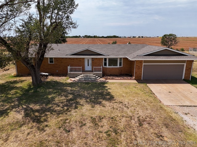 ranch-style home with a garage, a front lawn, and a rural view