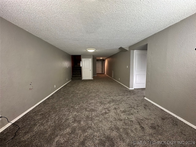 unfurnished room featuring a textured ceiling and dark carpet