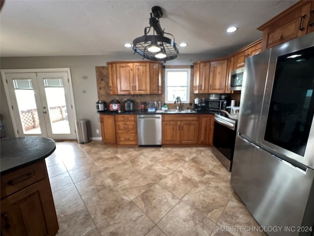 kitchen featuring tasteful backsplash, an inviting chandelier, light tile patterned flooring, appliances with stainless steel finishes, and hanging light fixtures