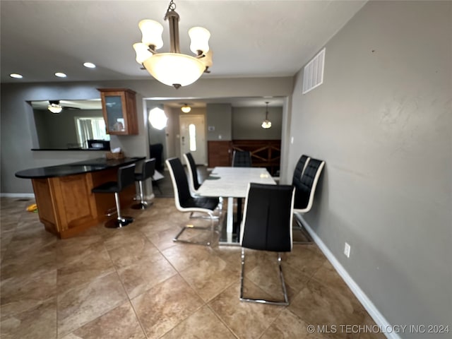 tiled dining area with ceiling fan with notable chandelier