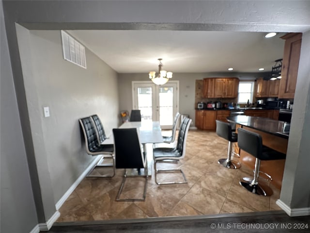 dining room featuring a notable chandelier, light tile patterned floors, a wealth of natural light, and french doors