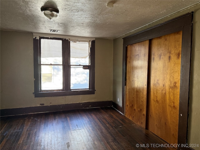 interior space featuring dark hardwood / wood-style flooring, a textured ceiling, and a closet