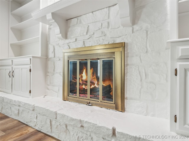 interior details featuring hardwood / wood-style floors and a stone fireplace