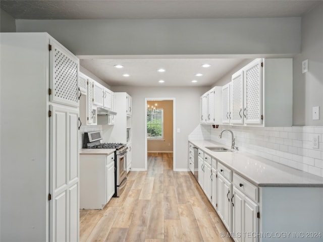 kitchen featuring white cabinets, decorative backsplash, sink, and stainless steel gas range