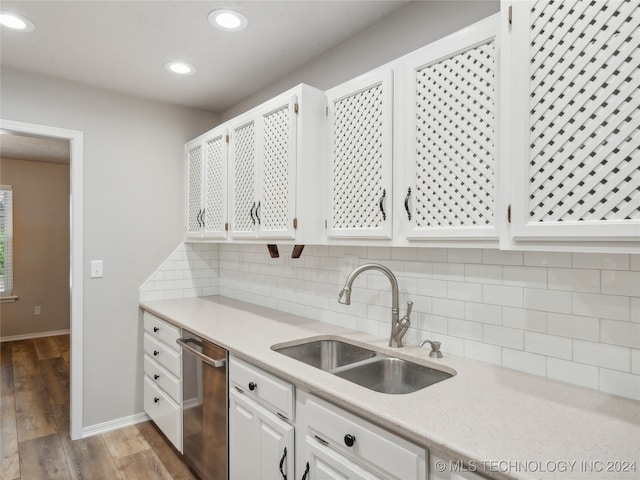 kitchen with backsplash, sink, dishwasher, white cabinets, and hardwood / wood-style floors