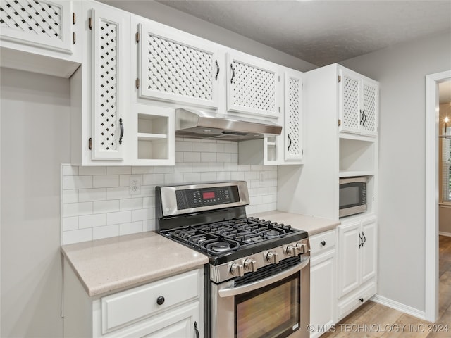 kitchen featuring stainless steel appliances, backsplash, extractor fan, white cabinets, and light wood-type flooring