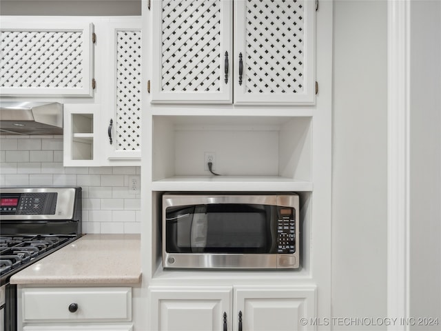 kitchen featuring backsplash, white cabinets, stainless steel appliances, and wall chimney range hood