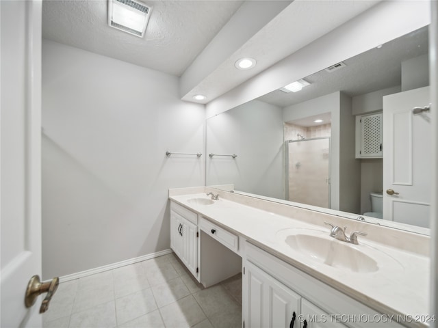 bathroom with an enclosed shower, vanity, toilet, and a textured ceiling