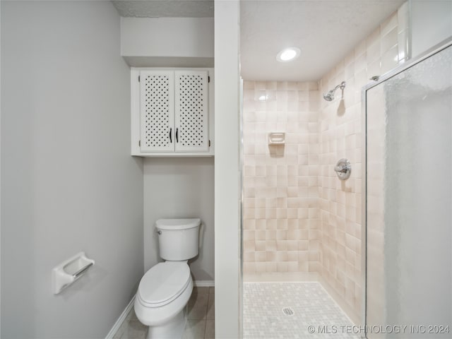 bathroom with tile patterned flooring, toilet, and tiled shower