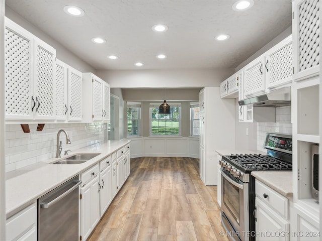 kitchen with tasteful backsplash, stainless steel appliances, sink, white cabinets, and hanging light fixtures