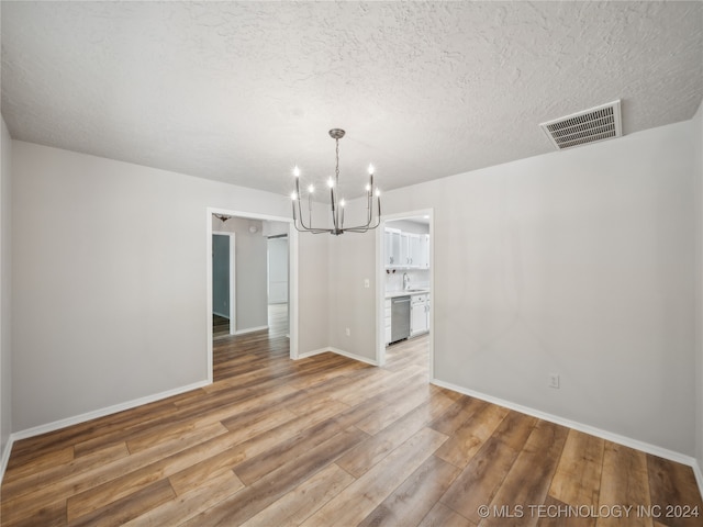 unfurnished dining area featuring hardwood / wood-style flooring and an inviting chandelier