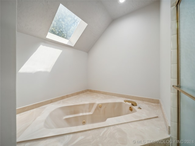 bathroom with vaulted ceiling with skylight and a tub