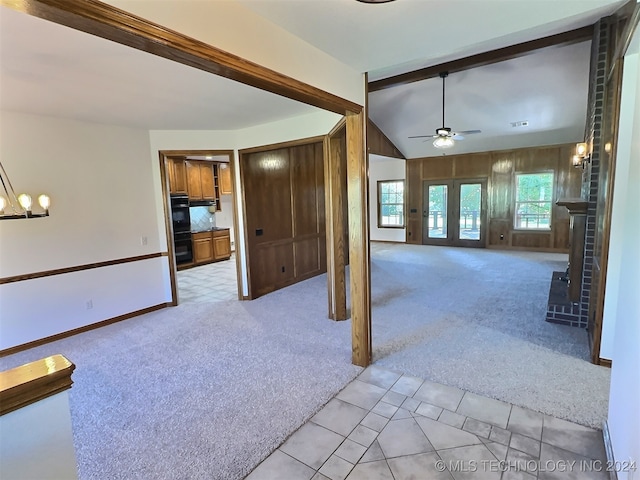 unfurnished living room featuring french doors, ceiling fan with notable chandelier, lofted ceiling, and light carpet