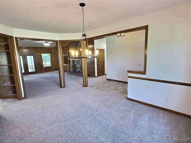 unfurnished dining area with light carpet and ceiling fan with notable chandelier