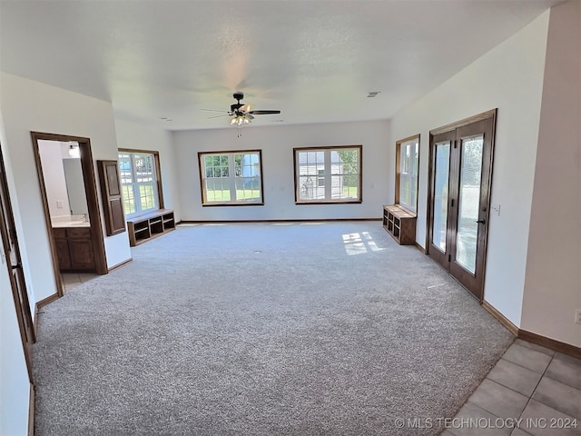 unfurnished living room featuring ceiling fan, a wealth of natural light, light colored carpet, and french doors