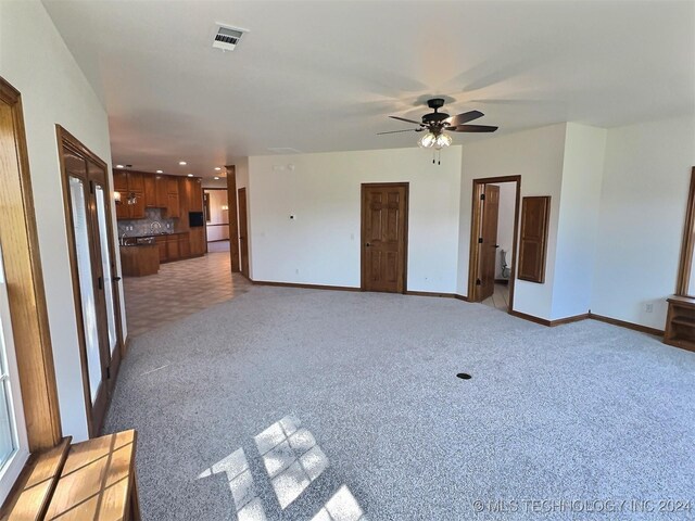 unfurnished living room with ceiling fan and light carpet