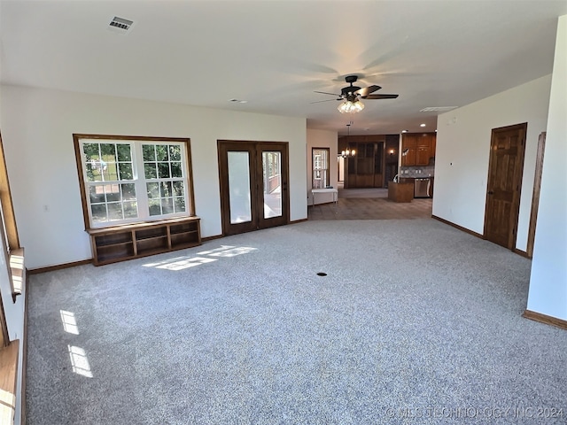 unfurnished living room with french doors, ceiling fan with notable chandelier, and light carpet